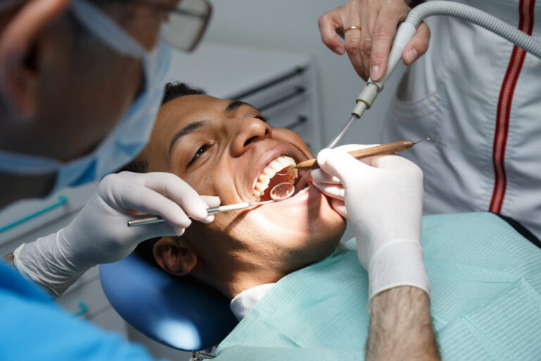 Dentist,Examining,Oral,Cavity,Of,Young,African-american,Man,Working,In