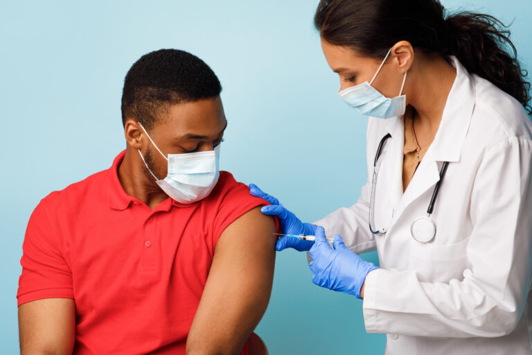 Black,Man,Getting,Vaccinated,Against,Covid-19,Over,Blue,Studio,Background